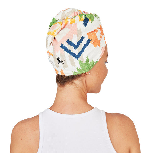 Woman wearing a colorful hair wrap with geometric patterns on a white background