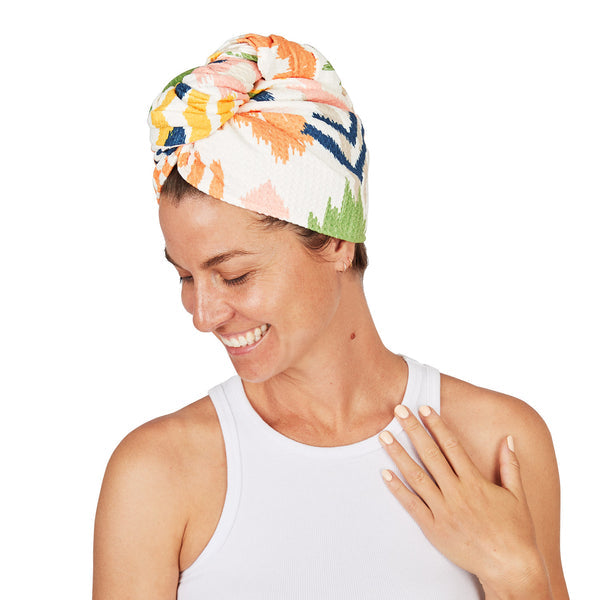 Woman wearing a colourful head wrap on a white background