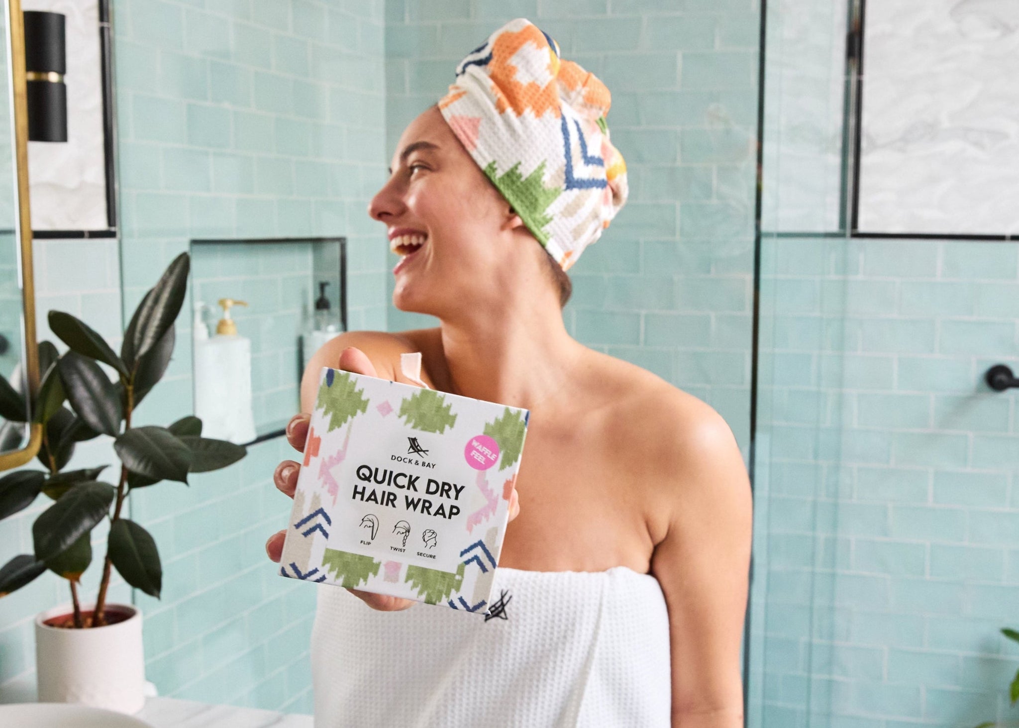 Person in a bathroom holding a quick-dry hair wrap with a plant and mirror in the background