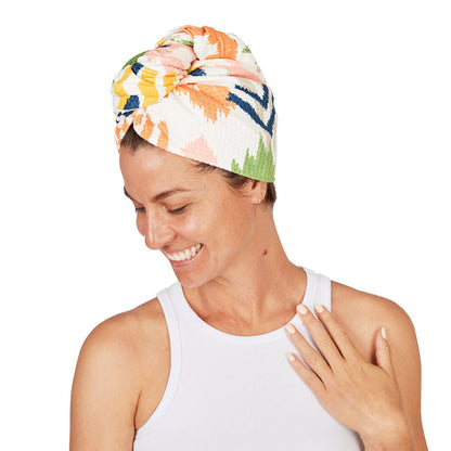 Woman wearing a colourful head wrap on a white background