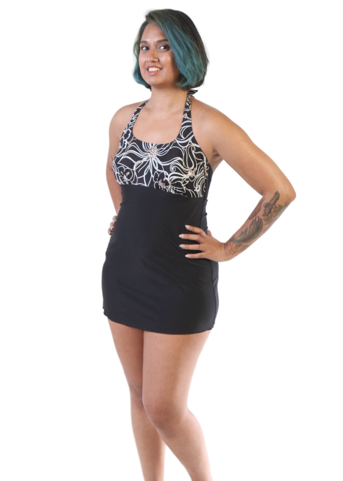 A model wearing a black floral one-piece swimsuit with a solid pattern on the leg area and a floral design on the chest.